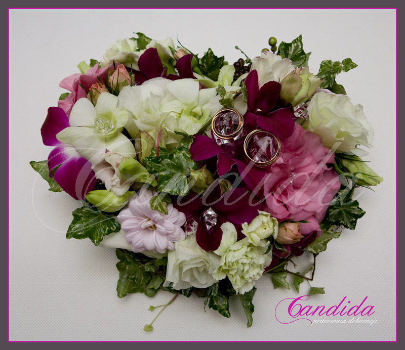 kwiatowa poduszka na obrączki  w formie serca wykonana z pistacjowej i różowej eustomy, storczyka dendrobium, goździka i margerytki