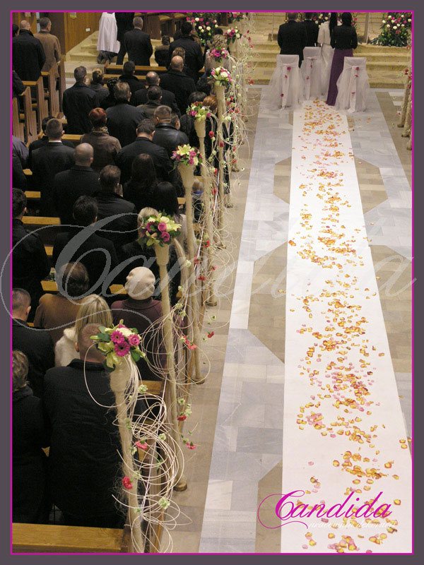 Dekoracja kościoła, nawy głównej. Do dekoracji użyto tuby z kwiatami i zwisającym rattanem. Biały dywan ozdabiają płatki róż.